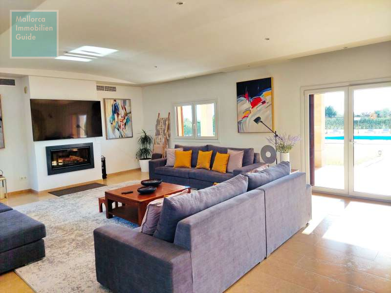 Wohnzimmer mit Kamin und Zugang zum Poolbereich